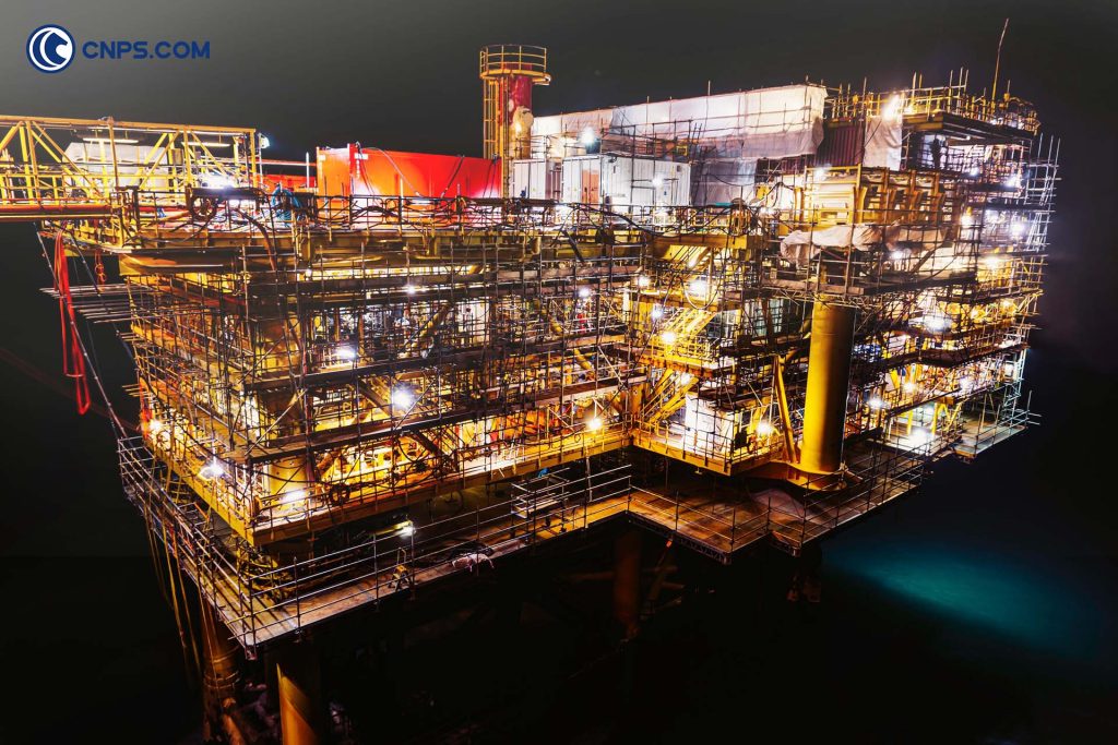 Illuminated offshore oil rig at night showcasing advanced petroleum extraction infrastructure.